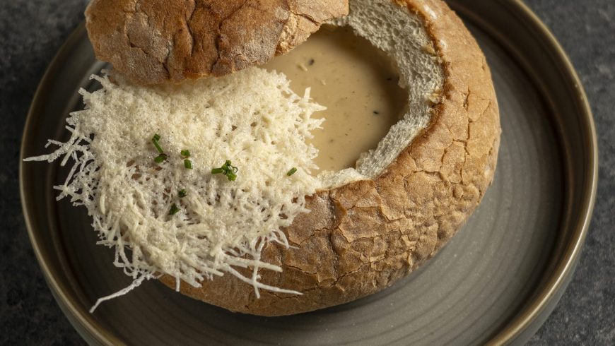 Creamy garlic soup with parmesan chips in a loaf